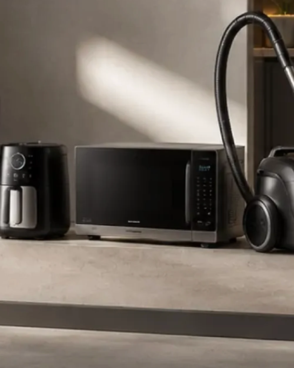 A stainless microwave oven and a compact air fryer on a concrete counter.
