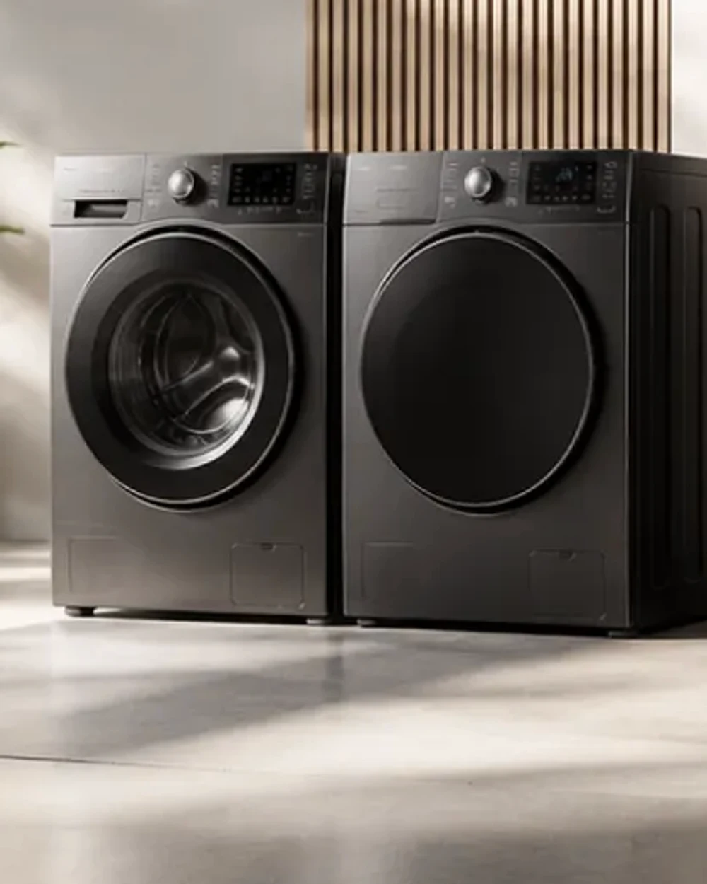 A front-load washing machine and matching dryer side by side against a fluted timber wall.