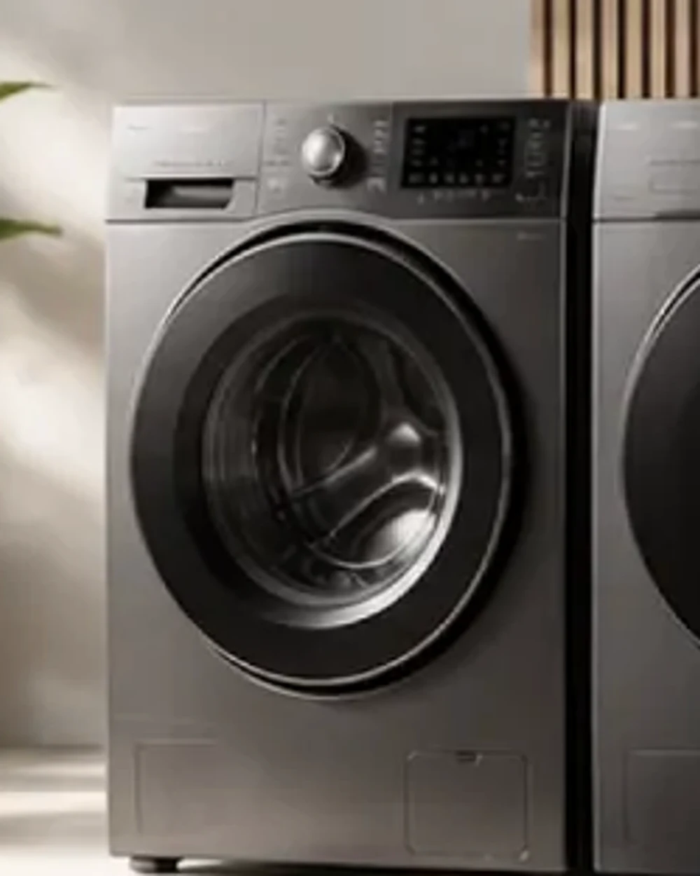 A graphite front-load washing machine beside its matching dryer on a polished concrete floor.